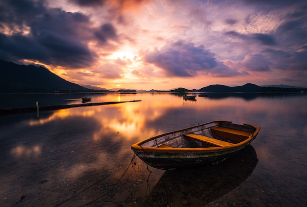 Free Photo beautiful shot of a small lake with a wooden rowboat in focus and amazing clouds in the sky