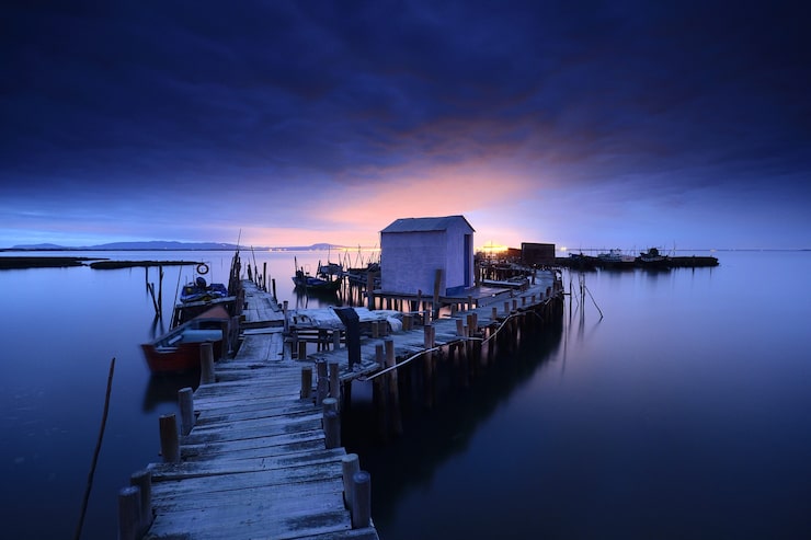 Free Photo breathtaking view of a wooden pier and a cottage over the calm ocean at twilight