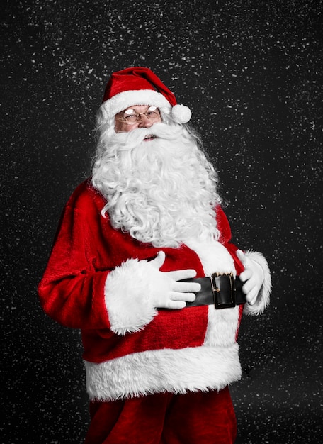 Free Photo cheerful santa claus touching his belly among snow falling