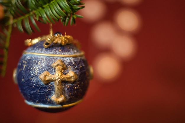 Free Photo close-up shot of isolated blue christmas tree ball decoration, with golden cross hanging on a green