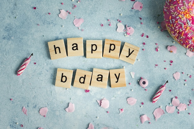 Free Photo flat lay of happy birthday wish in wooden letters with doughnut