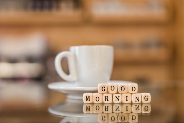 Free Photo good morning cubic blocks and coffee cup on reflective glass desk