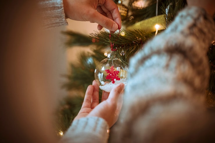Free Photo hands decorating christmas tree with baubles