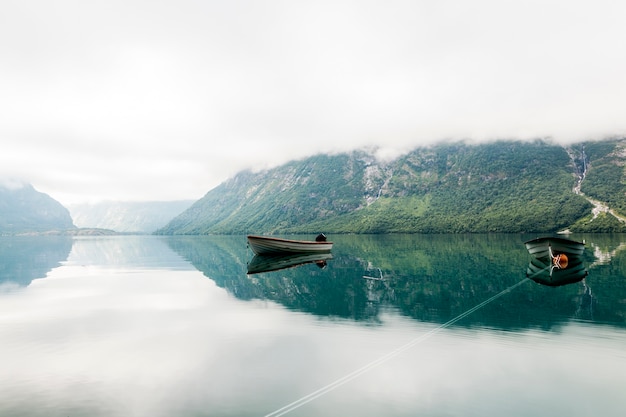 Free Photo lonely boats in a calm lake with misty mountain at background