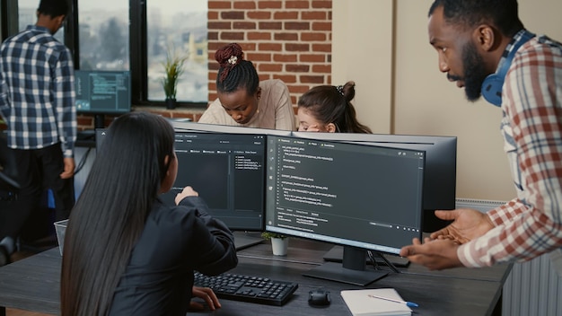 Free Photo mixed programers team working on group project on multiple screens showing running code in it startup office. coder pointing pencil at computer screen with software compiling code.