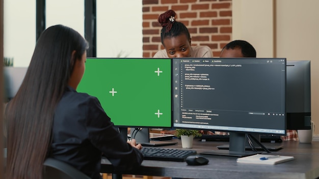 Free Photo software developer writing algorithm in front of computer with green screen chroma key mockup in ai development agency. cyber security app developer programming machine learning software.
