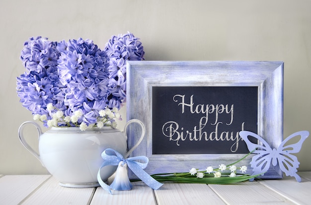Photo blue decorations and hyacinth flowers on white table, blackboard with text 