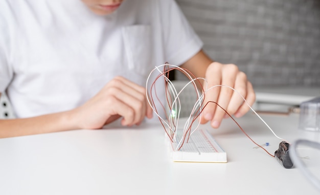 Photo boy hands working with led lights on experimental board for science project