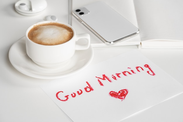 Photo cappuccino cup and good morning wish written by lipstick on white background