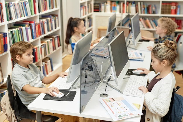 Photo children sitting at table with computers in lit programming class