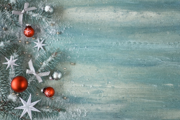Photo christmas background with fir twigs, light green and red trinkets and silver stars on light background, space