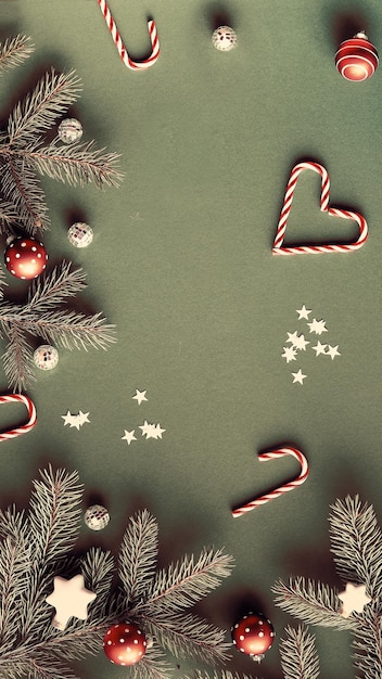 Photo christmas flat lay with fir twigs decorated with red baubles candy canes and paper star confetti