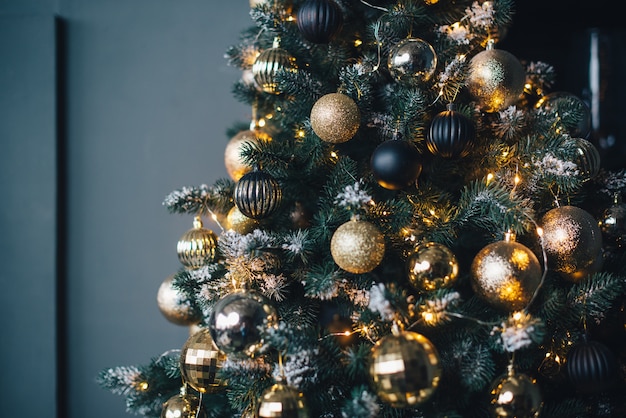 Photo christmas tree decorated with garlands and golden balls on a dark wall