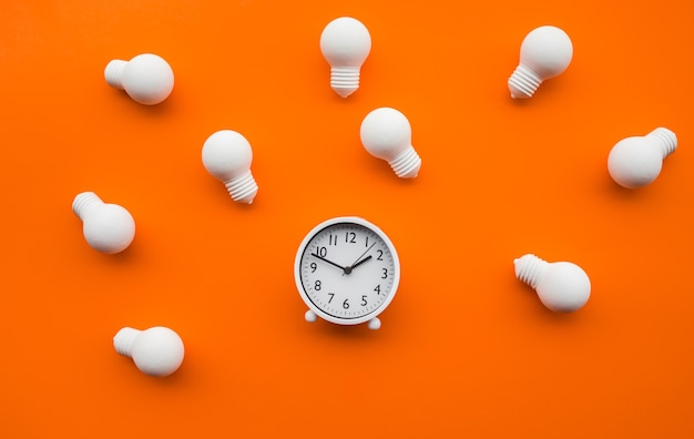 Photo a clock and lightbulbs on an orange background
