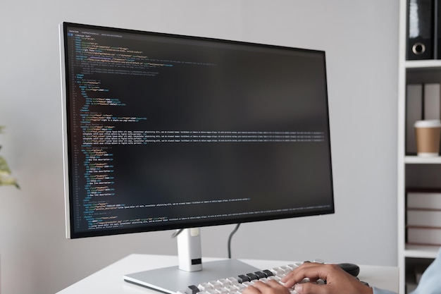 Photo close up view of programmer making software developer programming code with desktop computer in the office room