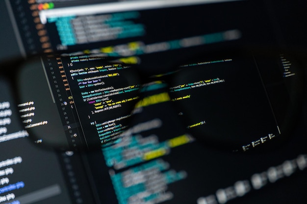 Photo closeup of computer screen with colorful code through eyeglasses software development programming coding and technology