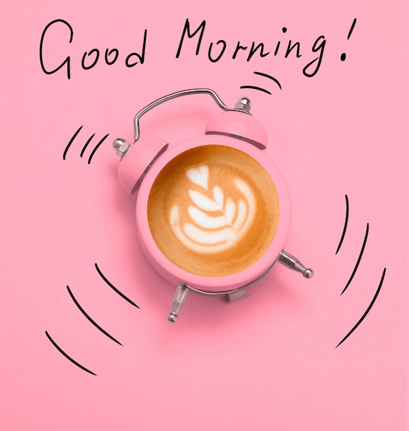 Photo coffee latte art in pink alarm clock on a pink and dodle good morning