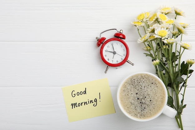 Photo a cup of coffee a bouquet of flowers and a card with the words good morning