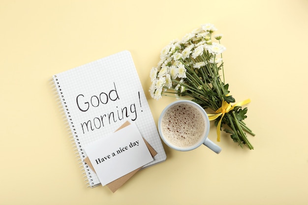 Photo a cup of coffee a bouquet of flowers and a card with the words good morning