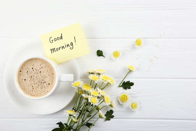Photo a cup of coffee a bouquet of flowers and a card with the words good morning