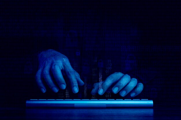 Photo cyberattack and internet crime hacking and malware concepts digital binary code data numbers and secure lock icons on hacker hands working with keyboard computer on dark blue tone background