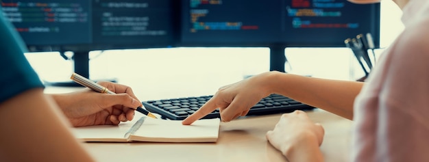 Photo female programer taking a note while young skilled web developer present program while computer displayed program code at modern office company java script web design concept burgeoning