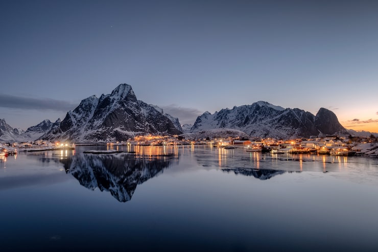 Photo fishing village illumination with mountain range reflection on coastline at dawn