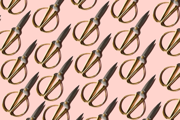 Photo gold scissors on a pink background regular pattern flat lay