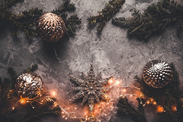 Photo holiday frame of christmas decorations on blue dark stucco concrete background with fir branch, gold balls, stars, christmas socks and toys. elegant new year`s. top view.