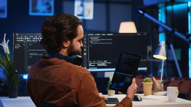 Photo it admin holding table using it as reference while coding on computer