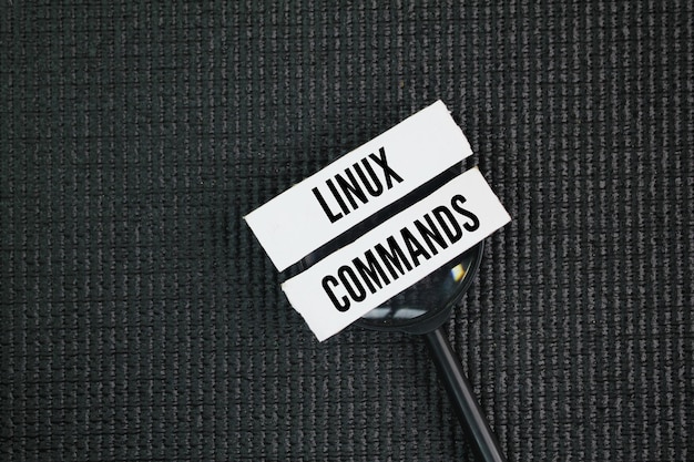 Photo a magnifying glass with the words linux commands instructions that users input into a terminal to in