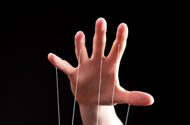 Photo manipulation authority concept hand with strings controlling manipulating smth abstract