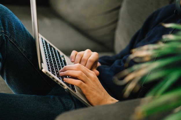 Photo midsection of man using laptop while reclining on sofa at home