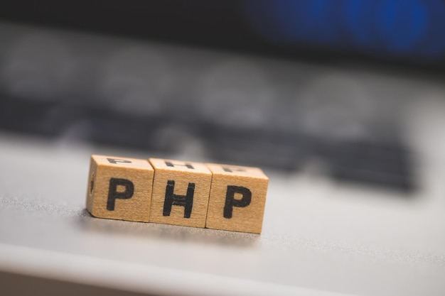 Photo php programming web language wooden cubes with letters php lying on a laptop concept