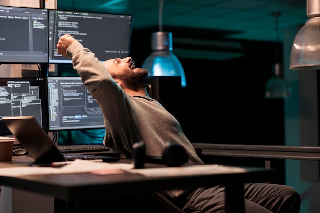 Photo pleased engineer celebrating ai software victory, feeling cheerful about app developing success after hours. smiling coder programming html script or source code with system database.