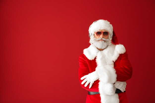 Photo portrait of cool santa claus listening to music on red