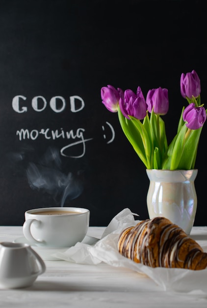Photo positive and happy breakfast setting with tulips bouquest, coffee and croissant