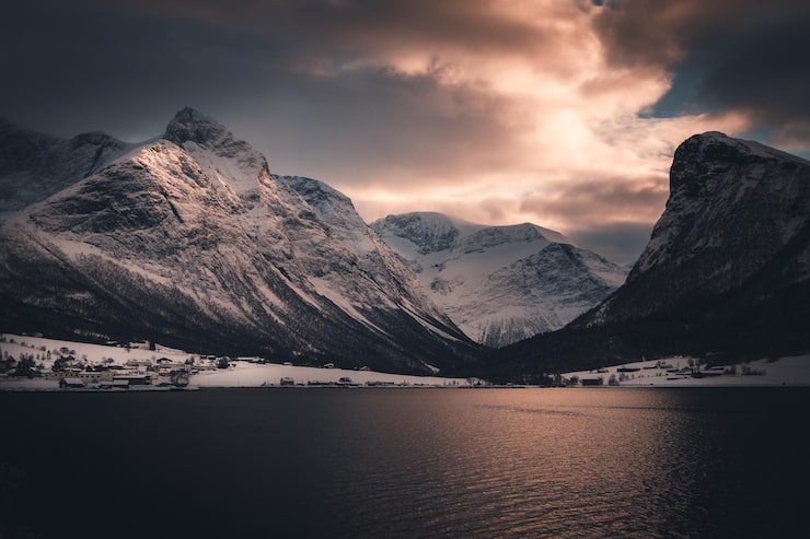 Photo scenic view of lake by snowcapped mountains against sky during sunset