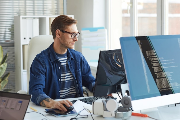 Photo side view portrait of modern it developer using computer in office while working on vr games and software, copy space