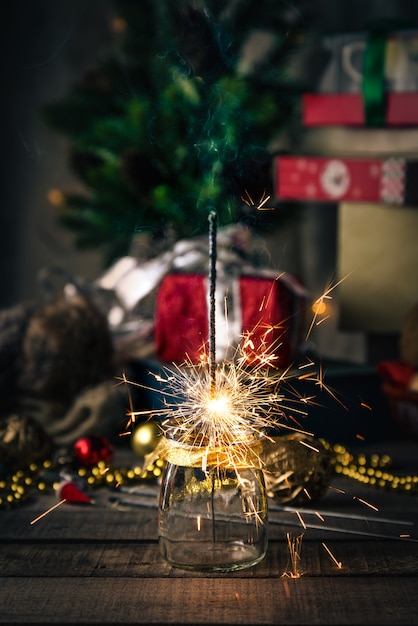 Photo sparkling bengal lights, christmas tree, decorations on wood