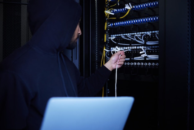 Photo thief programming and hacker stealing software website data and information on server on a laptop connection criminal and man hacking into a network for hardware coding and cyber crime at night