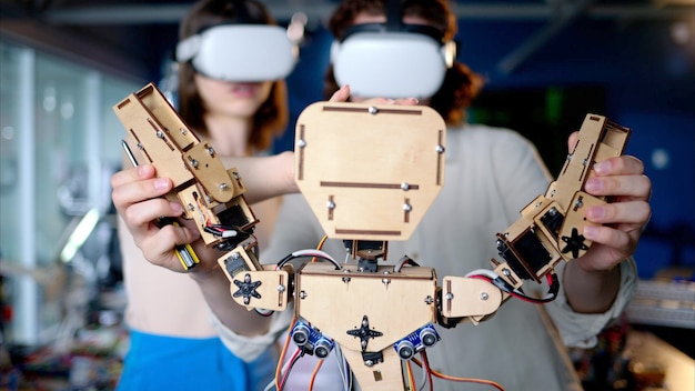 Photo two young engineers fixing a mechanical robot in the workshop using vr virtual reality headsets