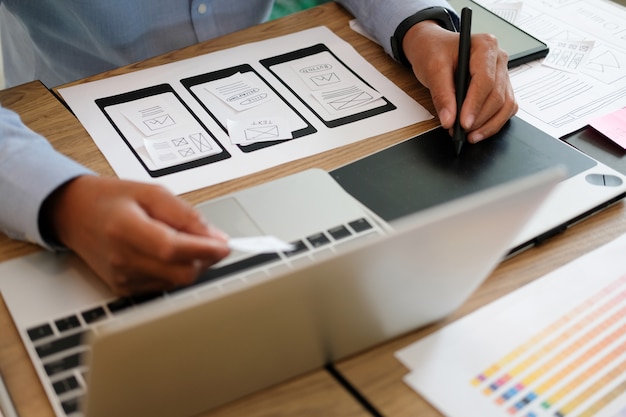 Photo user experience ux designer designing web on smart phone layout. 