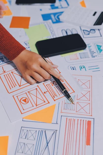 Photo ux ui designer testing prototype on a phone discussing and brainstorming on wireframes for a website and mobile app prototype in the concept of website and mobile application design concept