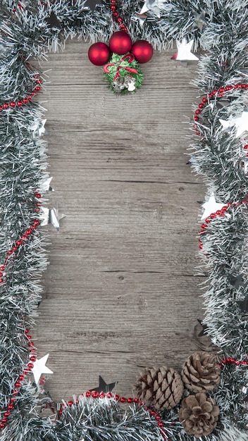 Photo vertical shot of a christmas background with decorations on a wooden surface with a copy space